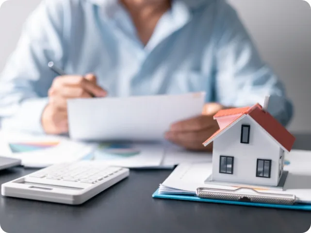 Person reviewing property expenses paperwork with calculator and house model