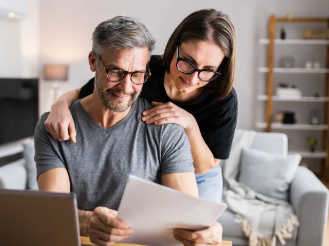 Smiling couple reviewing documents at home, planning a family investment limited company.